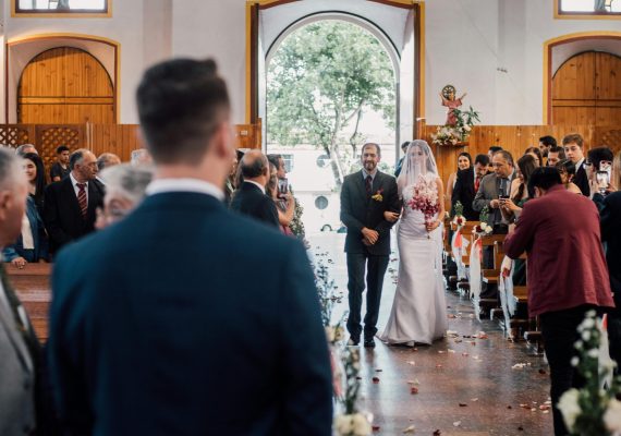 Bride and father walking down the aisle in a traditional indoor wedding ceremony.
