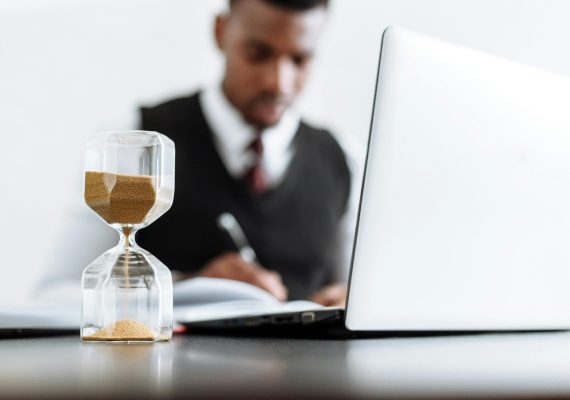 Businessman at desk with hourglass indicating time management and daily work routine.